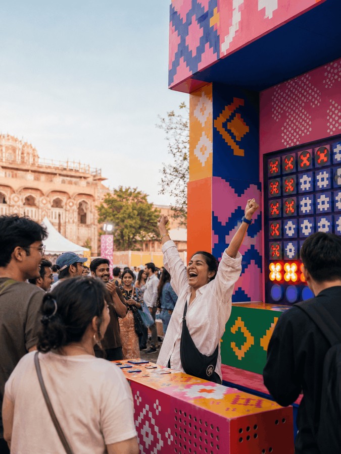 A crowd cheering at the giant Networking Games installation, Hawa Mahal in the background