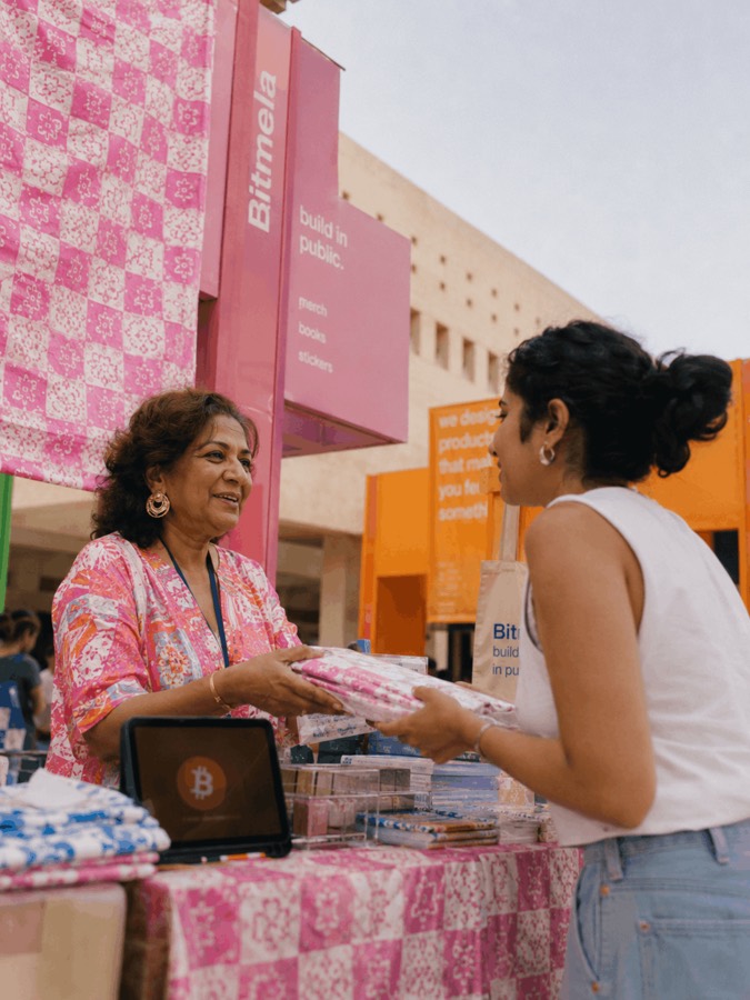 A vendor handing over merchandise at a Bitmela bazaar stall