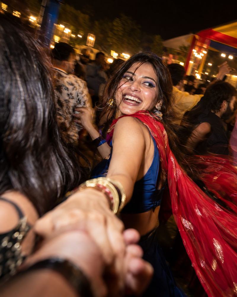A woman in a red dupatta dancing at night under string lights