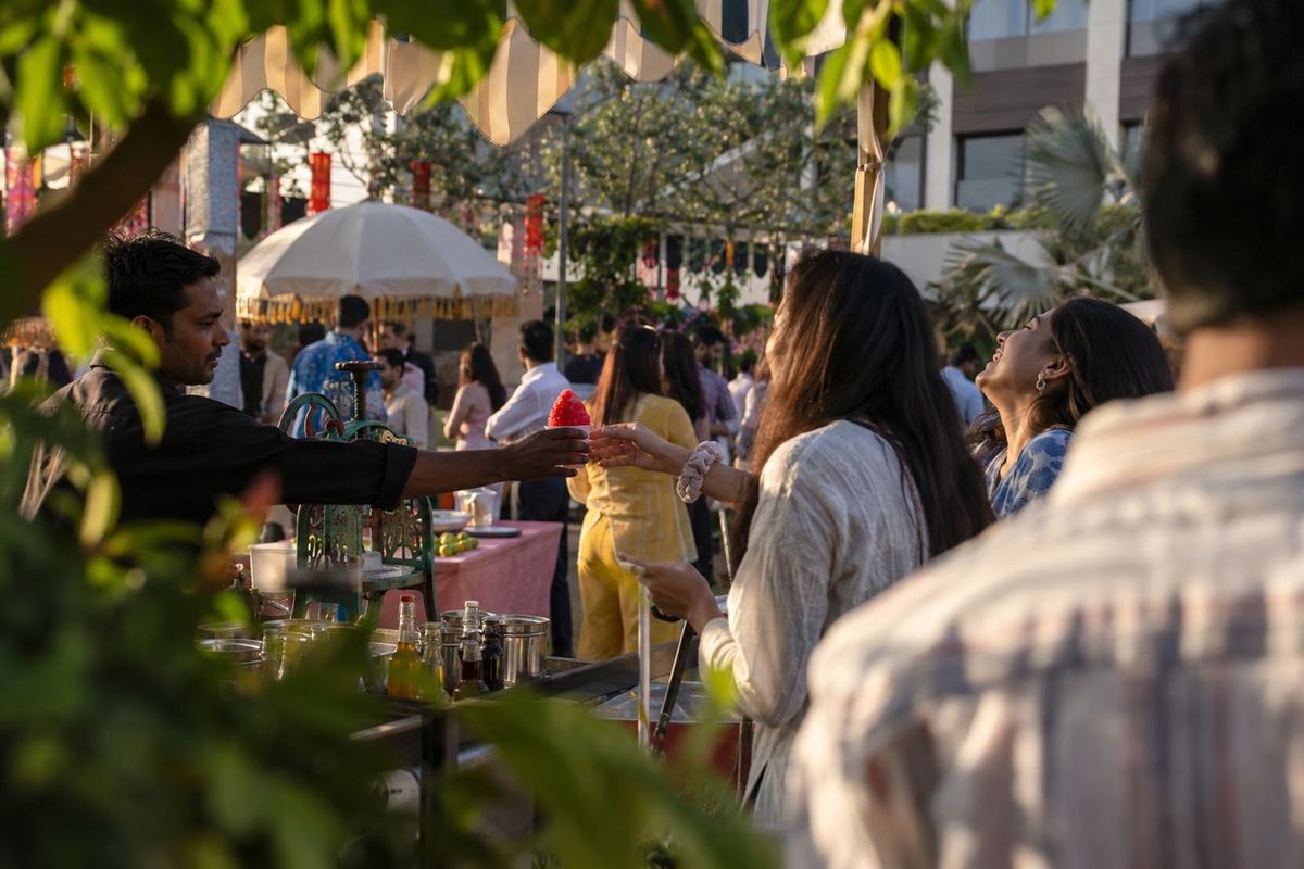 Crowds moving between food stalls and umbrellas on the outdoor mela grounds