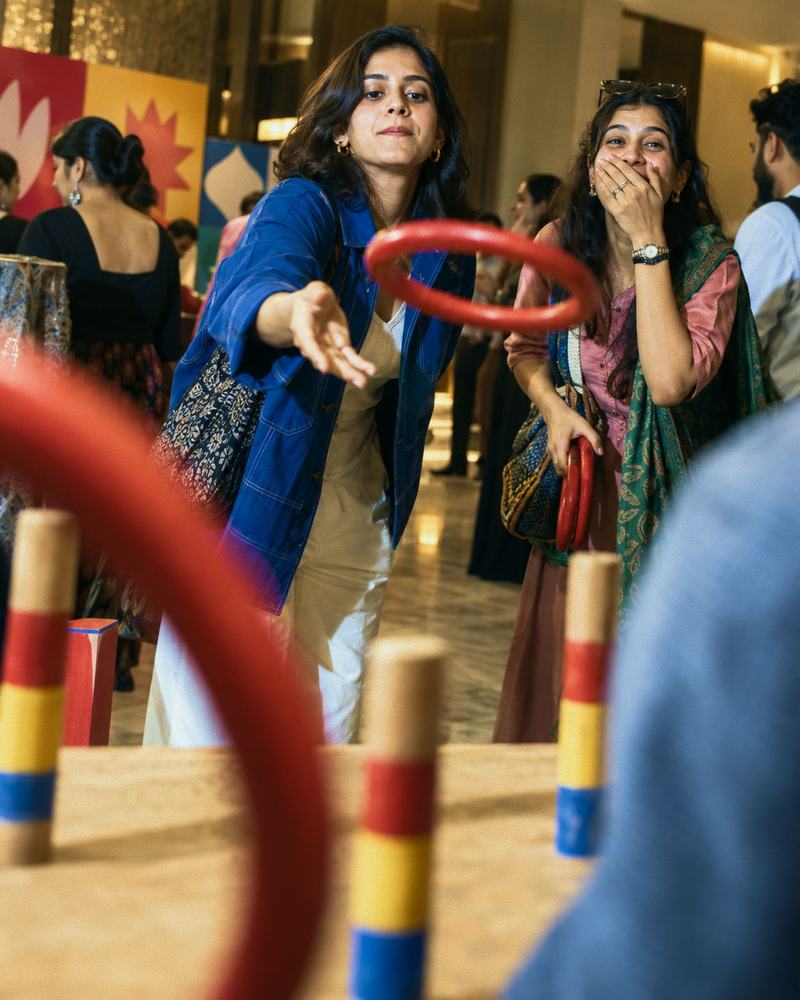 A woman throwing a ring at a ring toss game as her friend gasps